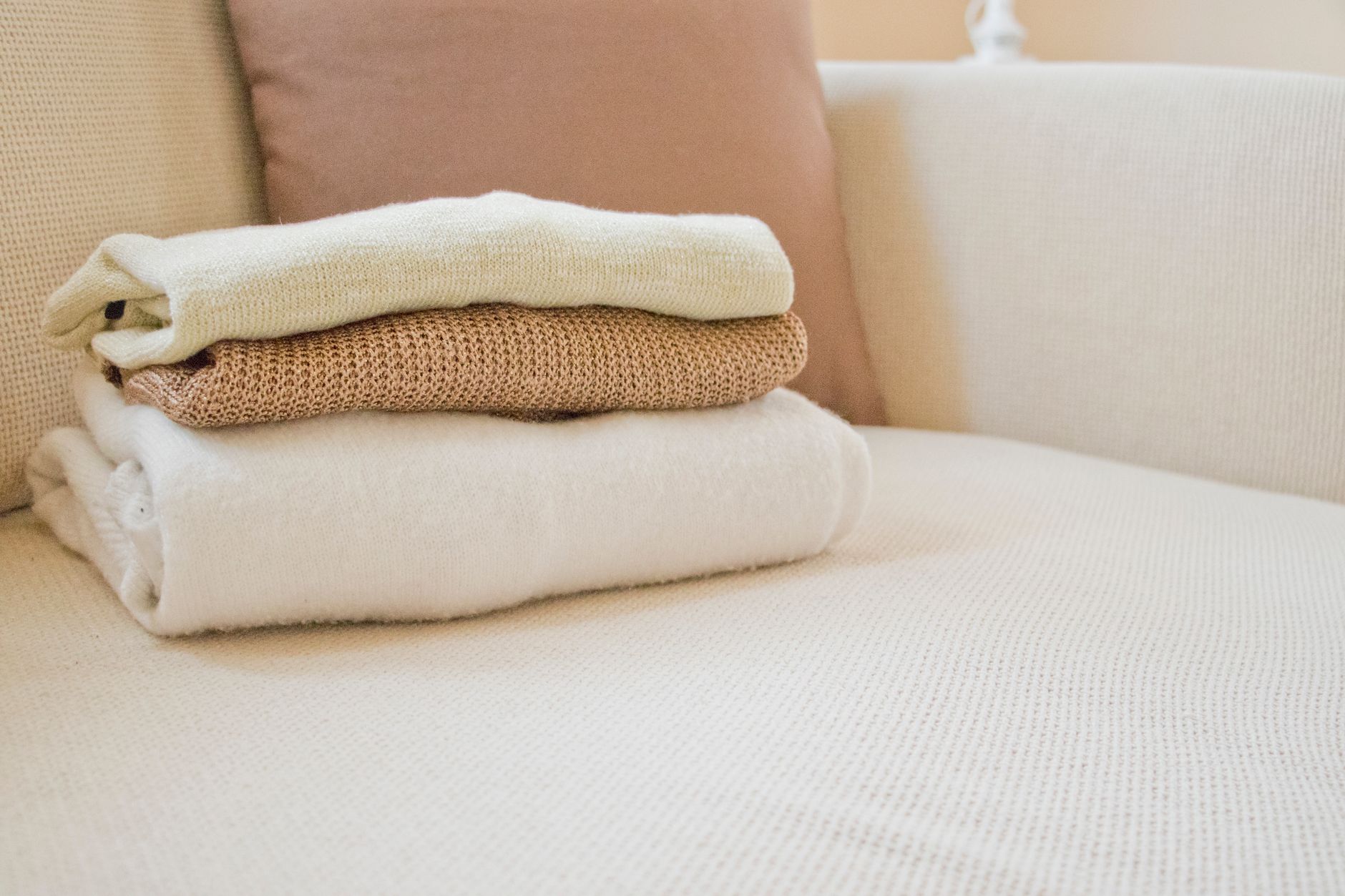 Folded merino knitwear pieces forming the foundation of a canal boat capsule wardrobe